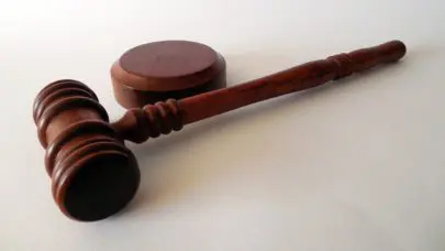 A wooden gavel laying on a white table, meant to represent the article "6 things you didn't know are illegal" by MMRBH Law Office.