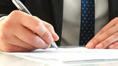 The hands of a personal injury lawyer as he signs documents, meant to represent the article "Finding the Best Personal Injury Lawyer" by MMRBH Law Office.