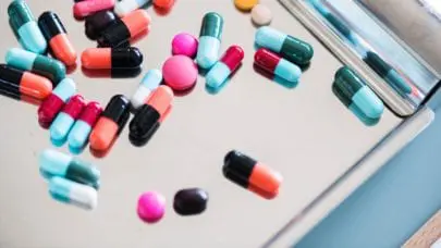 An assortment of colorful pills laid out on a metal pan, meant to represent the article "Unforeseen Opioid Addiction: Is There a Case?" by MMRBH Law Office.