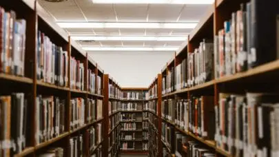 An isle of books in a library, representing the article "Injured on Campus: What Are Your Rights?" by MMRBH Law Office.