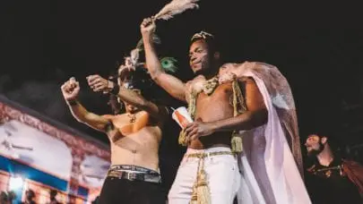 Two men adorned in Mardi Gras gear celebrating in a parade. Before you enjoy the festivities, make sure you understand the risk of personal injury during Mardi Gras.