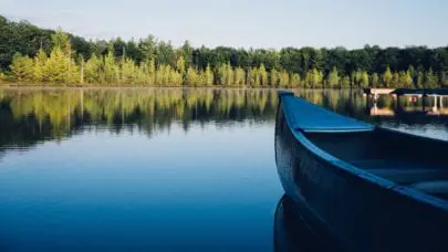 Photo taken from the POV of someone in a canoe looking over the water. Individuals in these circumstances should be aware of water injuries and liability before pushing off on their canoeing adventure.