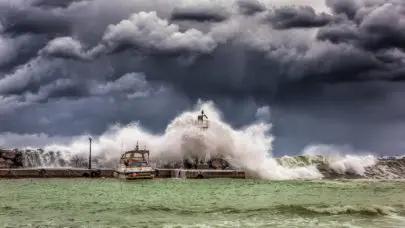 photo of a storm over the ocean. waves crest upon a pier, representing the risks of severe weather for offshore injuries.