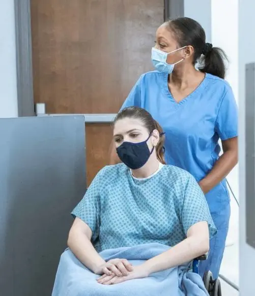 Image of a woman on a wheelchair being assisted by a nurse, meant to represent MMRBH Law Office's medical malpractice legal services.