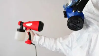 A person in a hazmat suit wearing a respirator holding a bottle of potentially hazardous spray. This photo is meant to represent Mesothelioma Mass Tort Law for MMRBH Law Offices latest article on the topic.