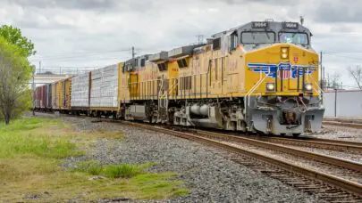 A union pacific train with a yellow engine car chugging along the tracks. This photo is meant to serve as a header image for the article" FELA Versus Workers' Compensation: What is the Difference?" by MMRBH Law Office.