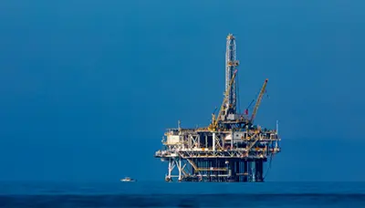 An offshore oil rig in the middle of the ocean, meant as a header image to represent the dangers of offshore drilling for the blog, "Is Offshore Drilling Safe?" by MMRBH Law Firm