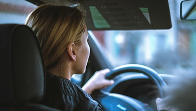 Pictured is a woman driving a car. The purpose of this photo is to represent someone driving without car insurance, for the blog "What to Expect When You're in a Car Accident with No Insurance" by MMRBH Law Firm.